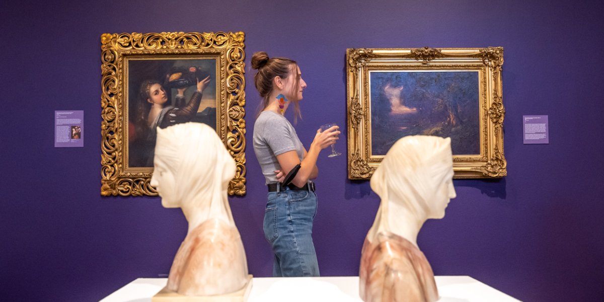 A student standing between two busts at the museum of art