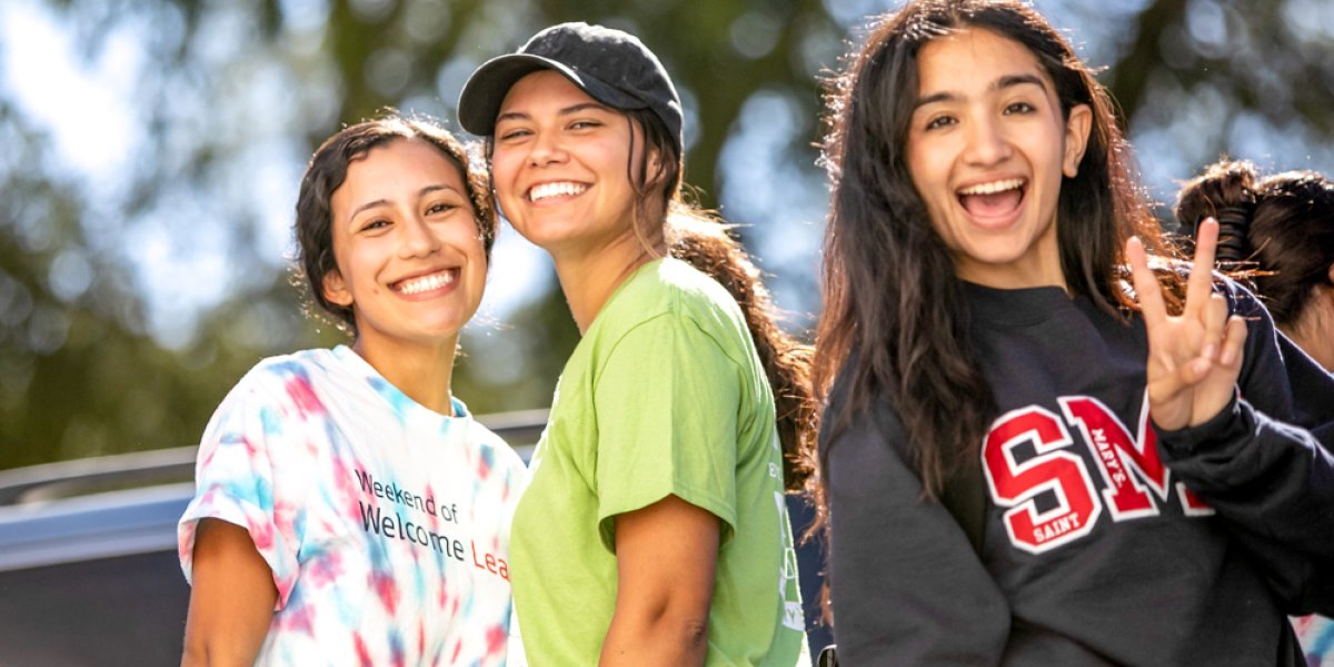 student showing peace symbol and smiling 