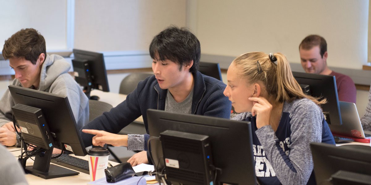 business analytics students pointing at data on screen