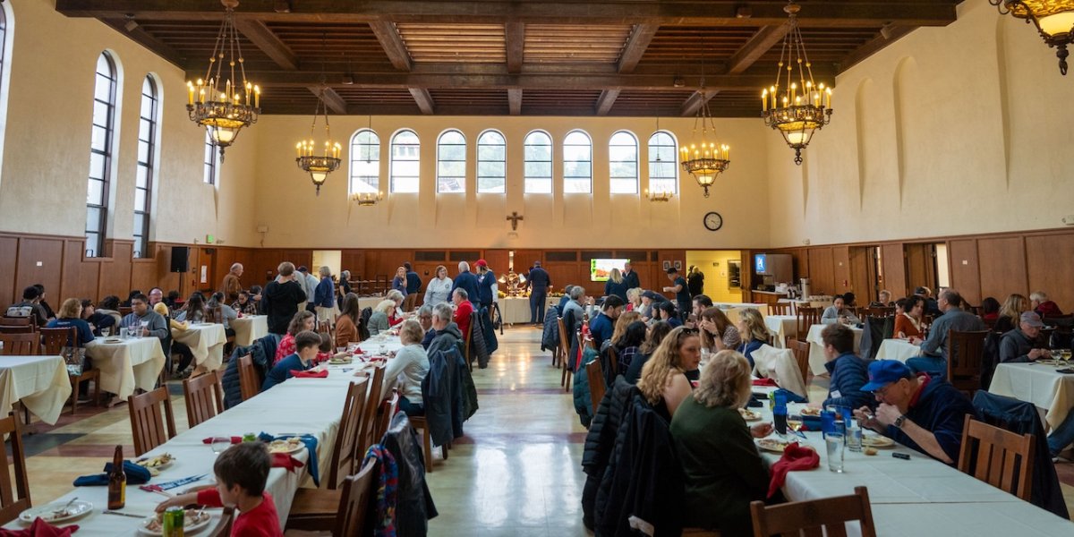 Hundreds sit at long tables inside the dining hall