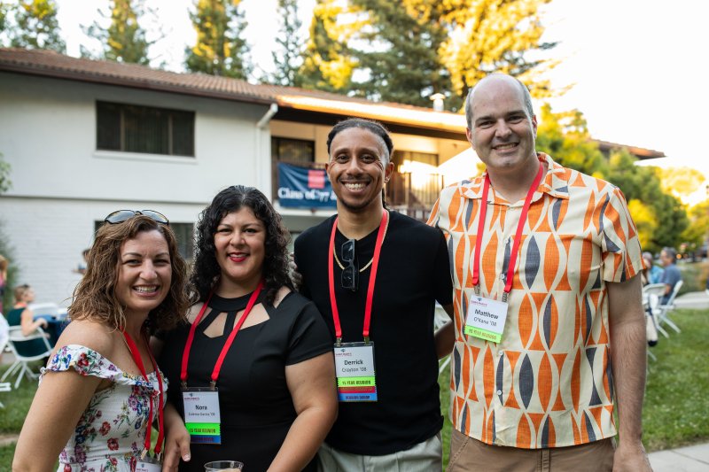 Four alumni smile in front of the Lower Townhouses at Reunion 2023