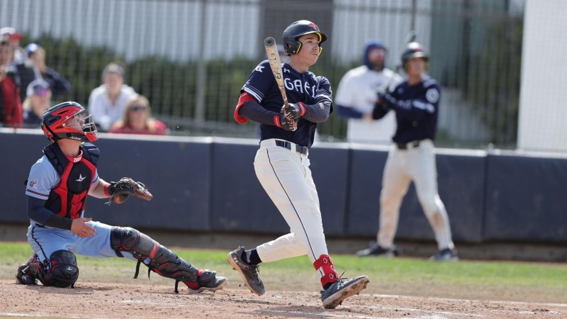 Baseball player Christian Almanza hits the ball while a catcher watches