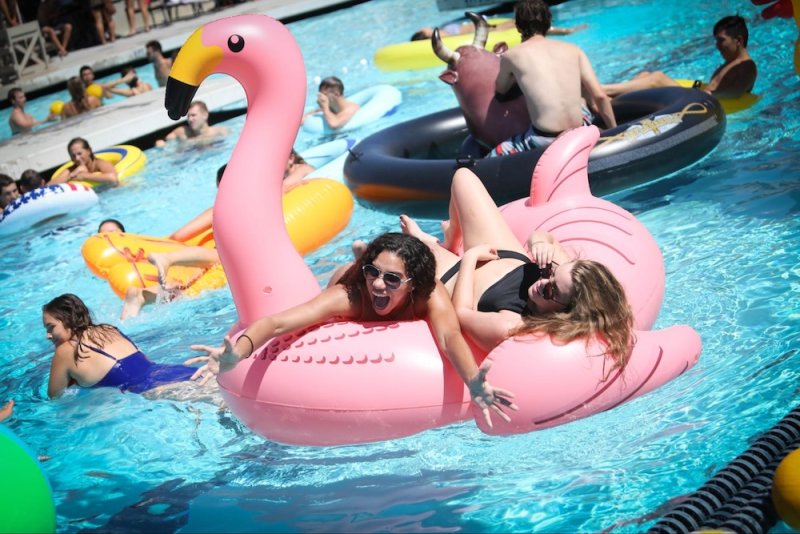 Students on pink flamingo float at pool party