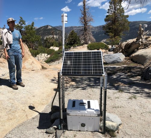 Adrian Madrigal approaching air quality monitor on a mountain