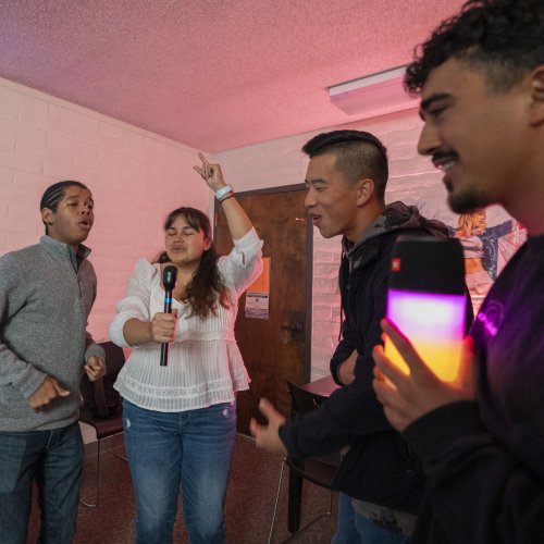 Four students in a townhouse residence hall sing karaoke 