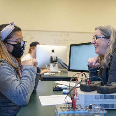Physics instructor talking with a student in lab