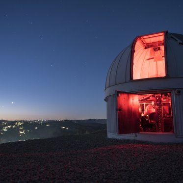 An observatory at the top of a hill at night