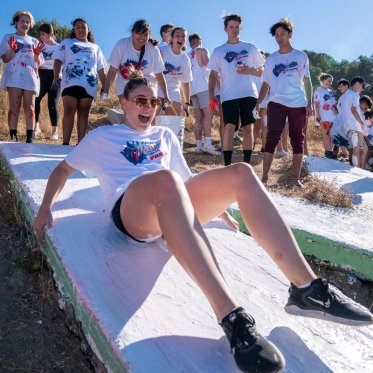 A student yelling and sliding down a letter at paint the SMC