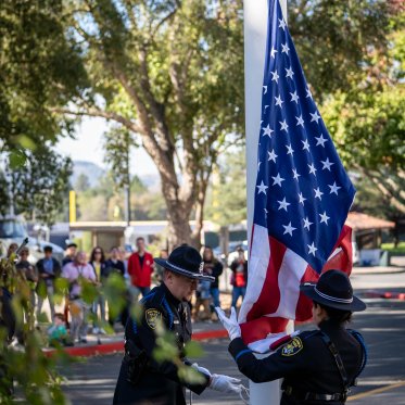 Honor Guard raising flag while crowd looks on