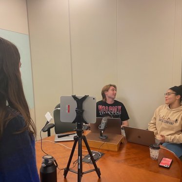 two women are sitting and talking where one lady is looking at them 