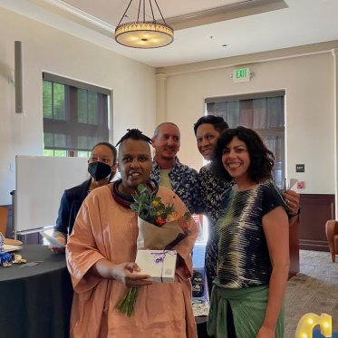 people standing together Infront of a desk and women is holding bouquet 