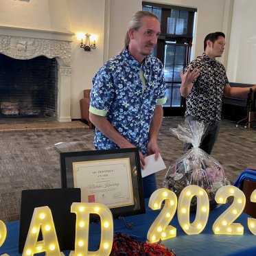 man wearing blue shirt standing and holding a paper