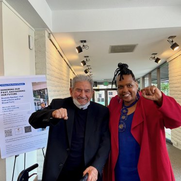 two men standing next to a poster and showing fist