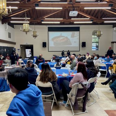 student sitting around tables and listening to the speech