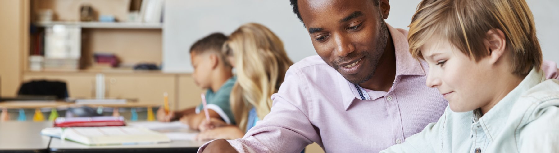 Male teacher teaching a student in the classroom