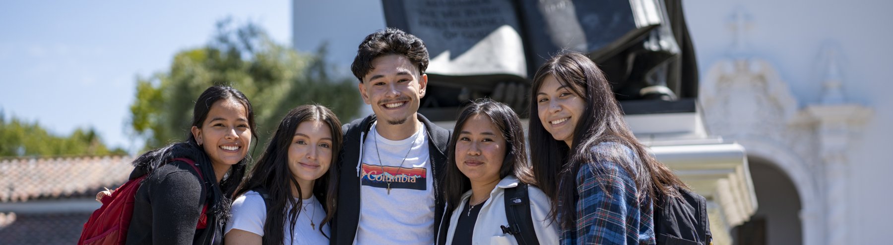group of students with backpacks standing together and smiling on the first day of school