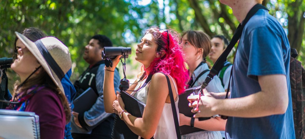A bird watching class outside with binoculars