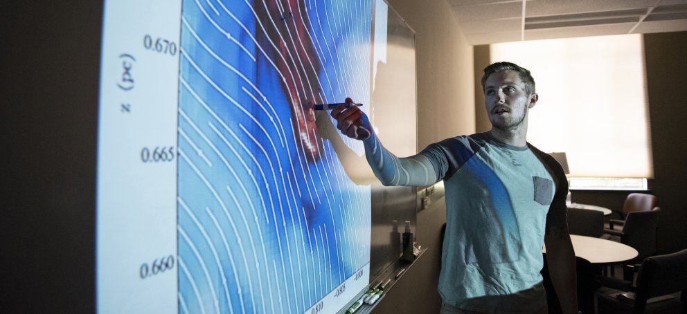 A student pointing to a chart on a white board