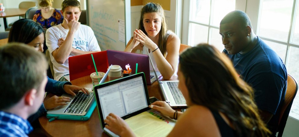 Writers and a Writing Circle Facilitator discussing a paper in the Writing Center.