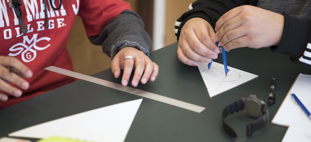Two students using a ruler and protractor to accomplish math