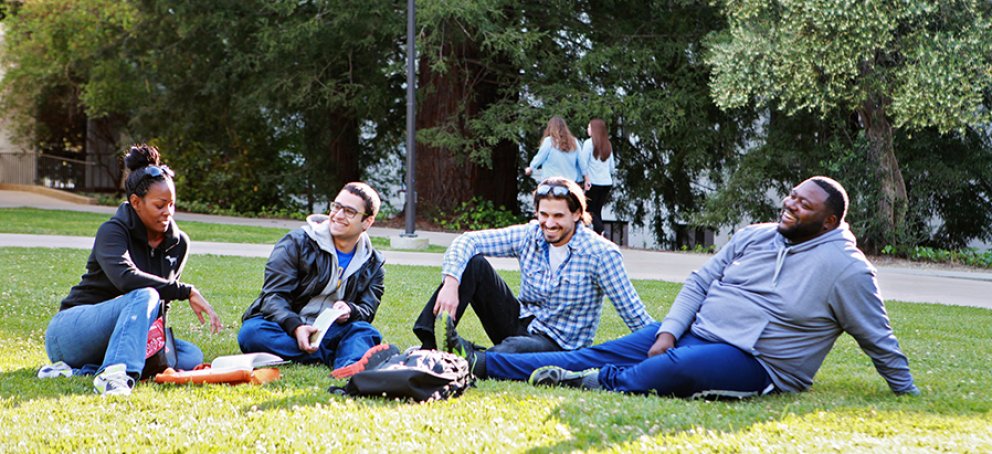 Students sitting on the grass in front of De La Salle Hall