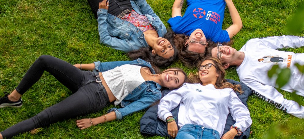 five students on grass in a circle