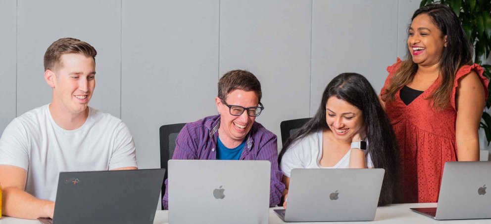 Students laughing studying in front of laptops