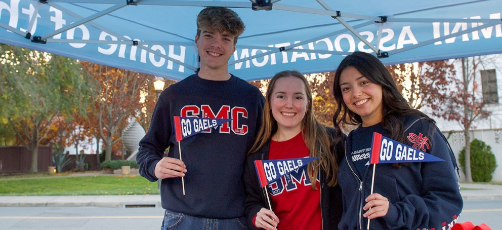 three students smiling outside