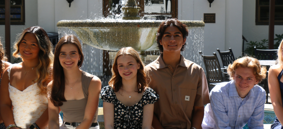 7 people sitting in front of a fountain
