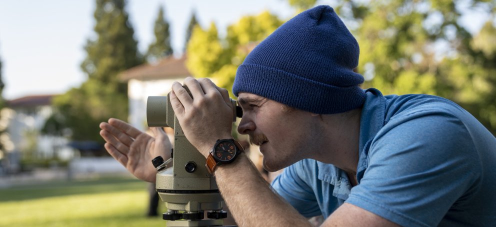 Male student looking through survey tool on lawn of SMC campus