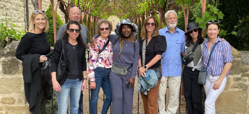 Nine alumni pose for a picture under vines in Spain