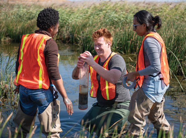 Three science students in a creek doing environmental studies