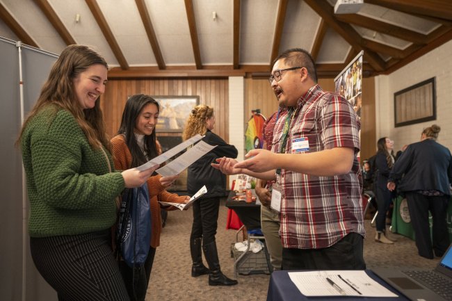 Guy in plaid talking to 2 women at career fair