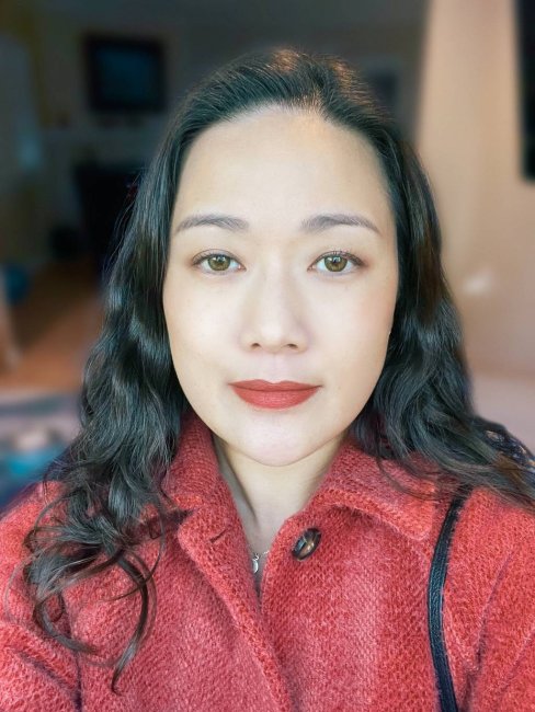 Headshot of Prof. Hilda Ma in red coat background is blurred