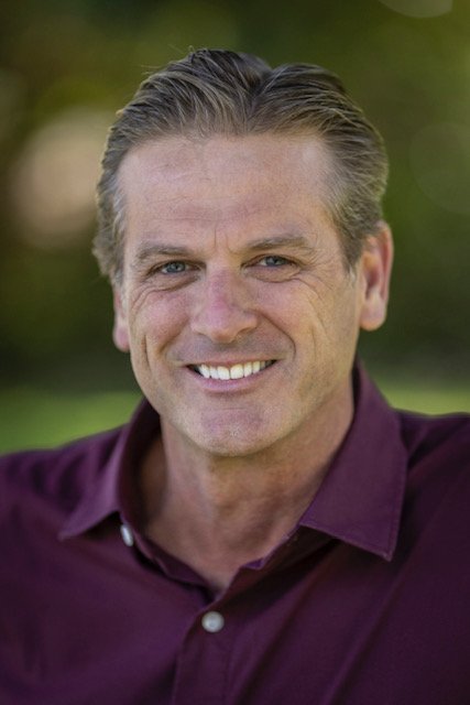 Stewart Burr in a purple polo shirt smiling at camera, against a blurred background