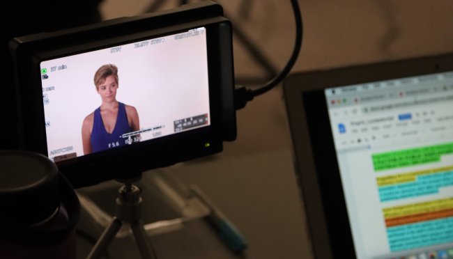 In a video production class, student Molly Gilbert appears onscreen next to a laptop