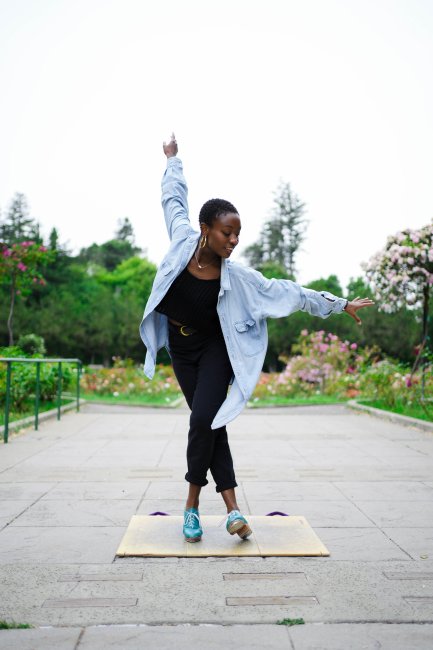 Micah Sallid in the middle of a dance pose outside in a garden.