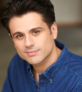 A headshot of Alexander McDaniel, wearing a blue collared shirt