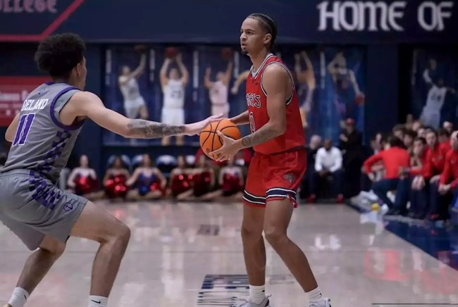 Men's basketball player Mikey Lewis holds the basketball and prepares to shoot against Portland in February 2025