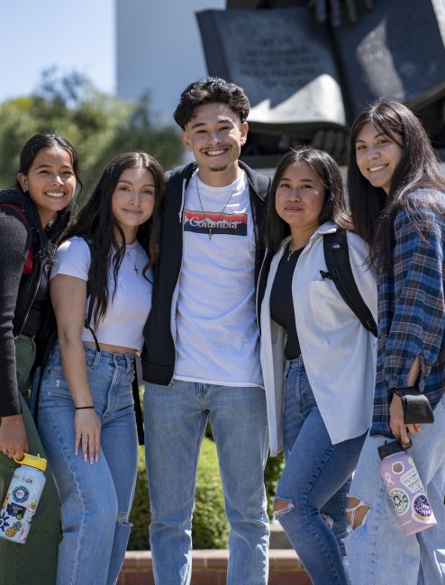 Five students standing in front of De La Salle statue at SMC