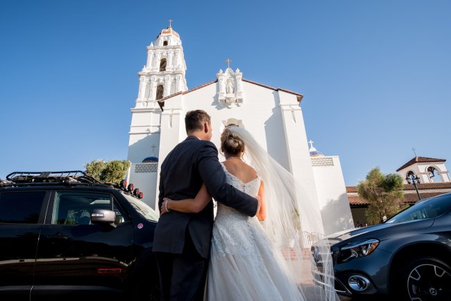 A wedding couple stands facing the SMC Chapel with their backs to the camera