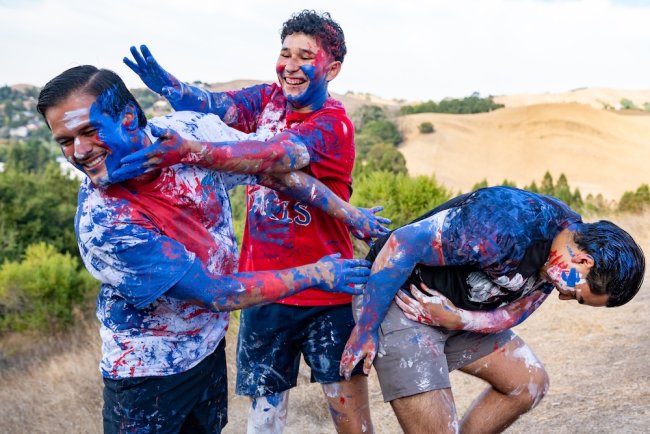 Three male students covered in paint as part of Paint the SMC in 2025