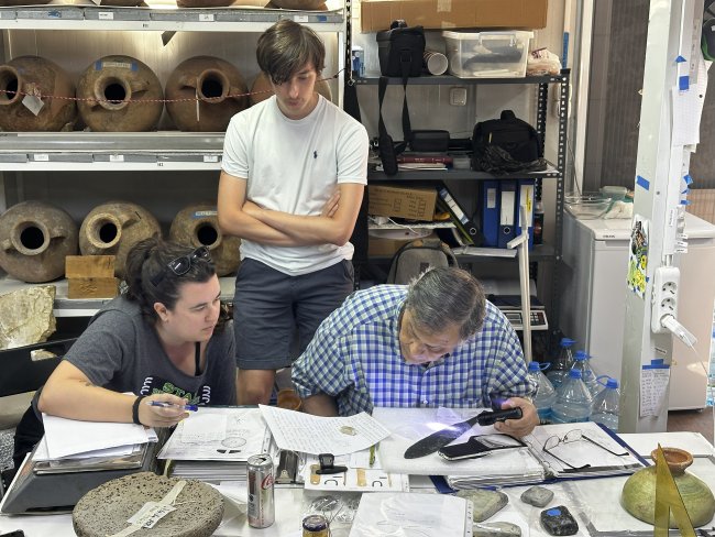 Christopher Bakerr observing artifact inspection in lab