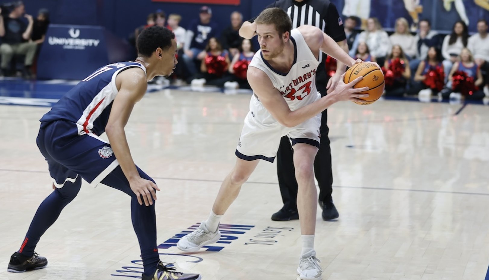 Men's basketball player Luke Barrett holds the ball away from a Gonzaga player