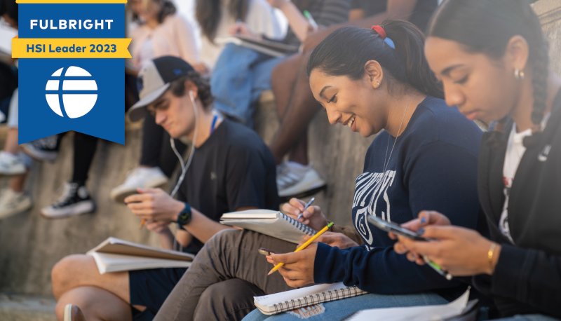 Fulbright HSI Leader 2023 badge and SMC students working with notebooks and phones