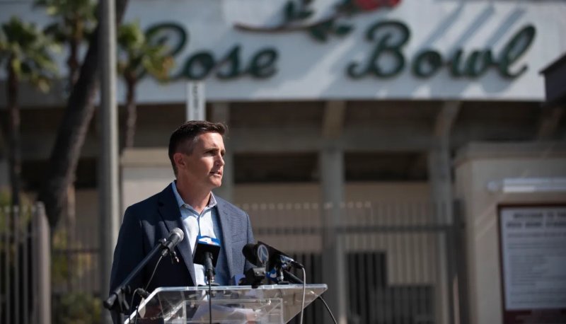 Jens Weiden speaks at a podium with the Rose Bowl stadium and logo in background