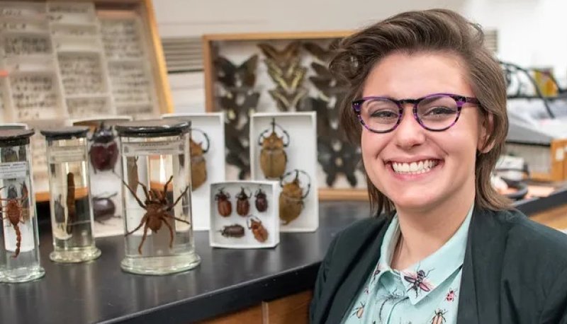 Abbey Hayes '16 smiles next to insects on display in a science lab