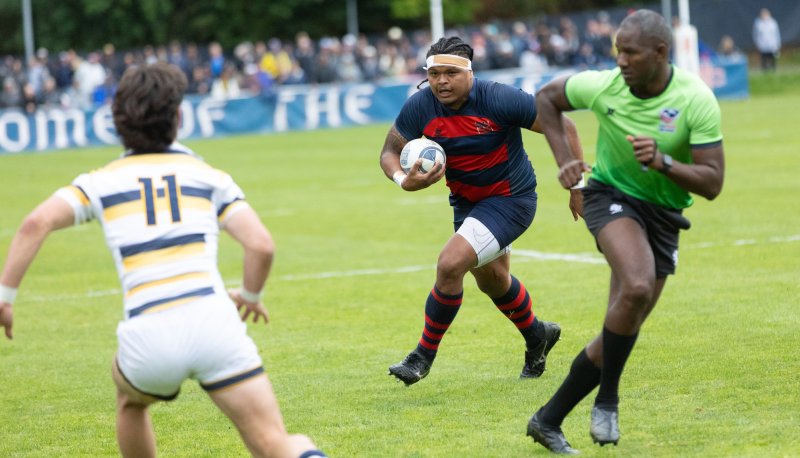 SMC men's rugby player King Matu ’24 runs with the ball with a referee to his left and a Cal defender in front of him, April 2024