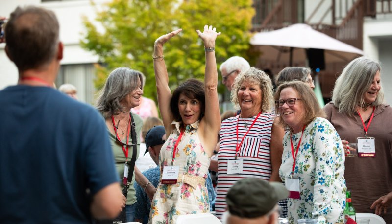 Jeanette Leong '84 holds her hands in the air to greet a friend at Reunion