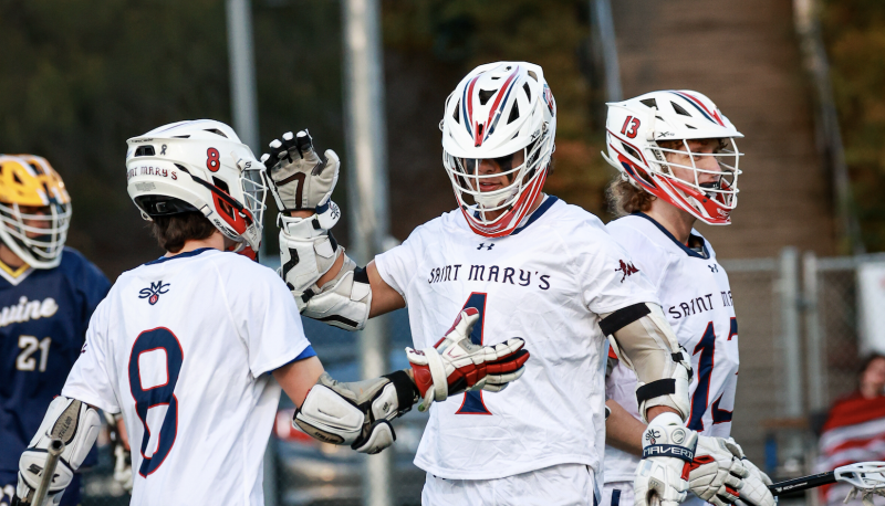 Men’s Lacrosse team members Tim Daly (No. 8), Dario Caccia (No. 4), and Hayden Bradley (No. 13) celebrate after scoring against UC Irvine in a match on the Recreational Turf Field last Spring. / Photo by Ashleen Rai ’26